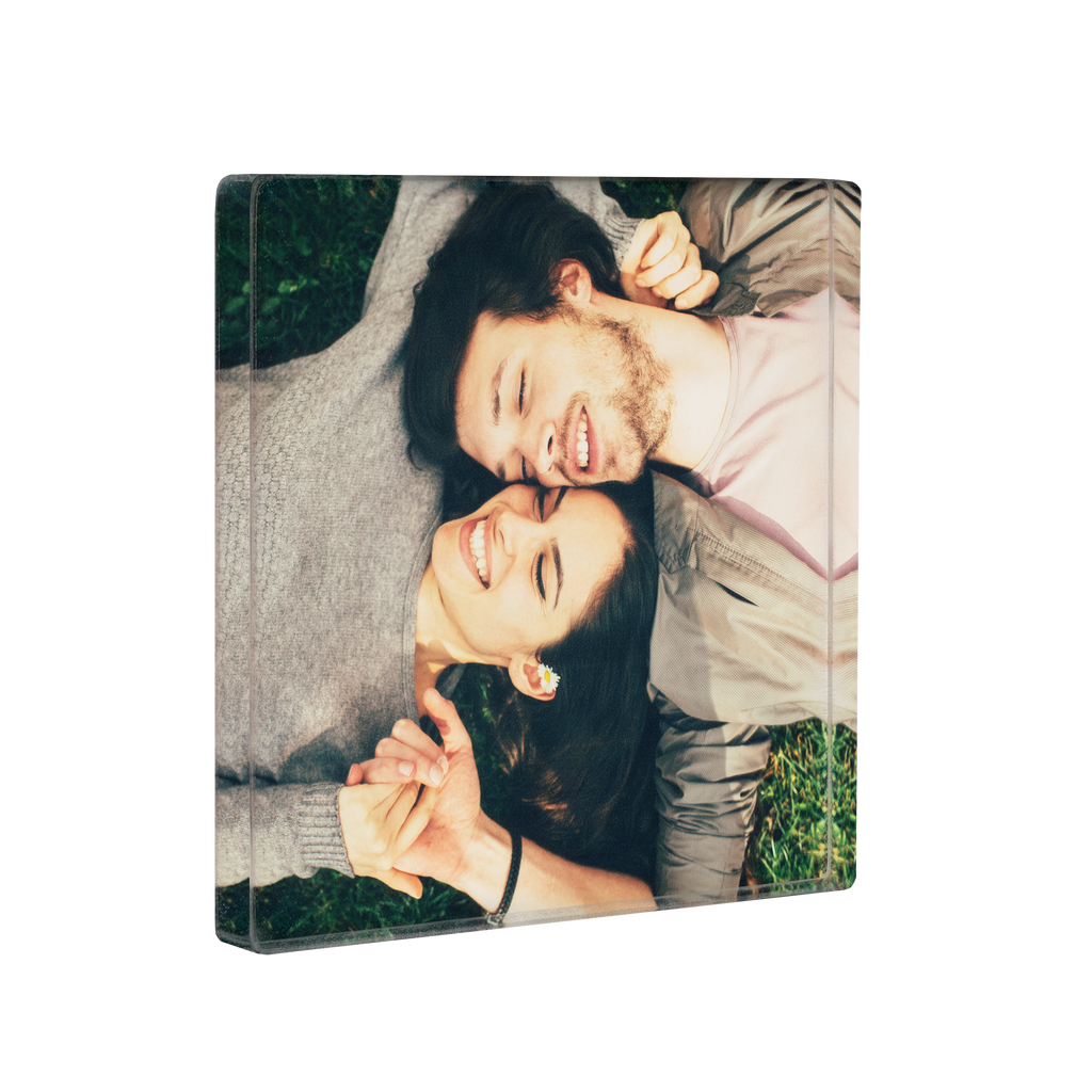 Two people lying on grass, smiling with their heads close together, captured in a Fuji Personalized Photo Products Acrylic Square Photo Magnet.