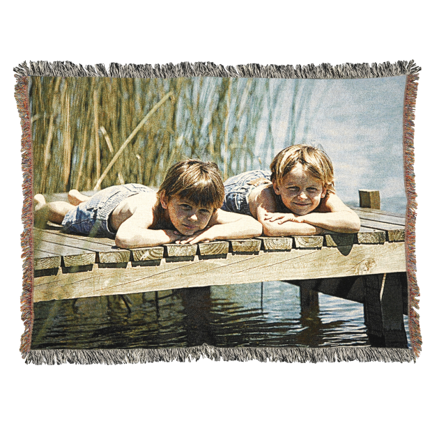 Two children laying on a Fuji Personalized Photo Products Woven Throw Blanket on a dock.