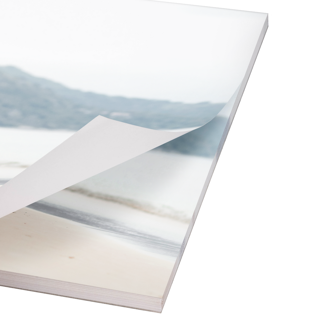 A close-up view of a Fuji Personalized Photo Products notepad planner opened to a weekly planning spread, with pages lifting in a breeze, revealing a beach landscape photograph.