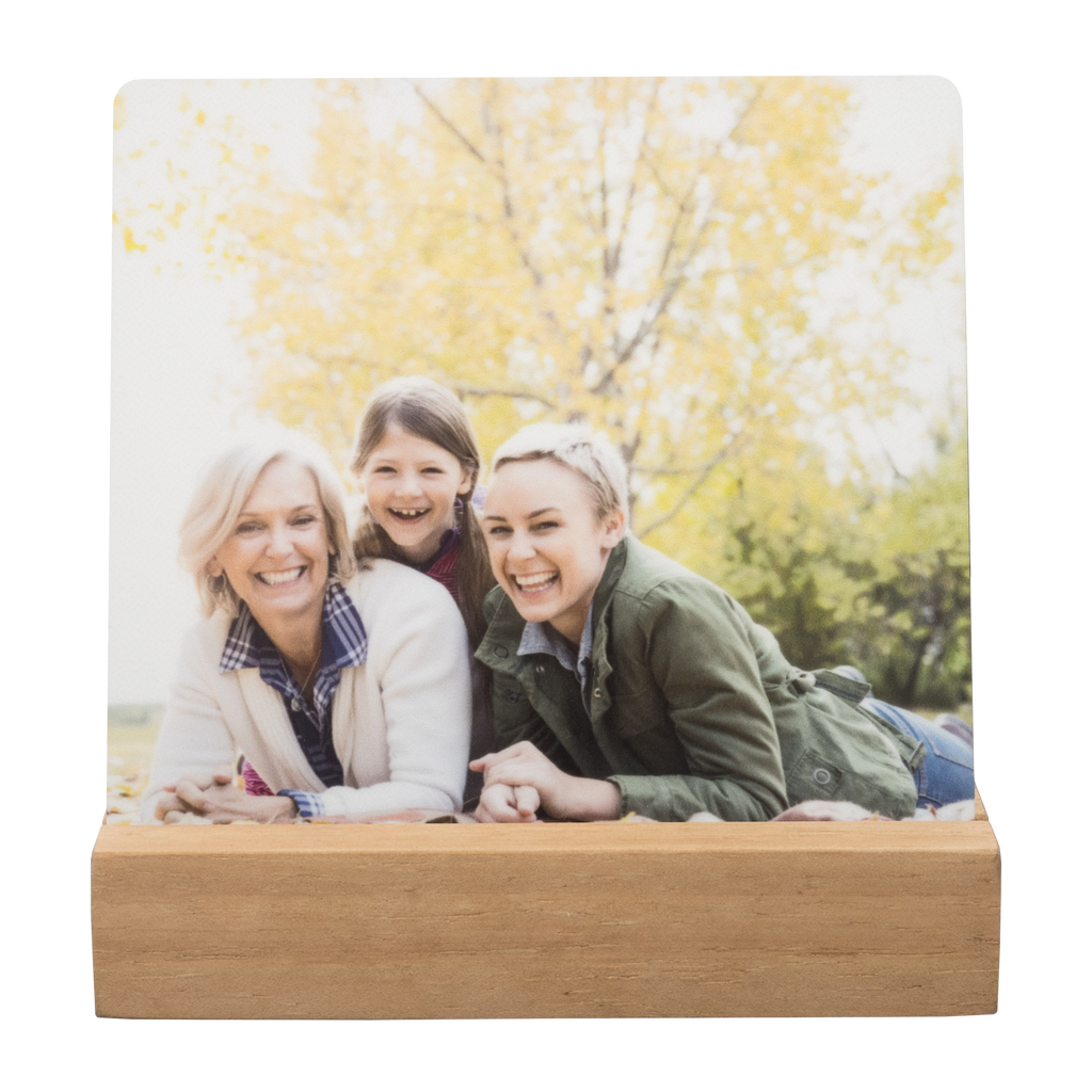 A family is laying on a wooden bench in front of a tree, captured in a photo that ensures long-lasting memories through a Fuji Personalized Photo Products Metal Desk Print.