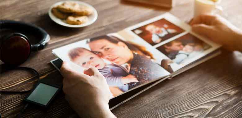 A person is holding a photo book with a photo of a family on it.
