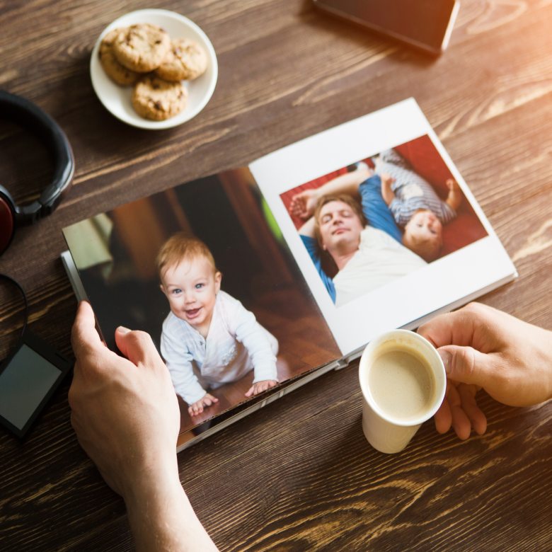 A person holding a photo book and a cup of coffee.