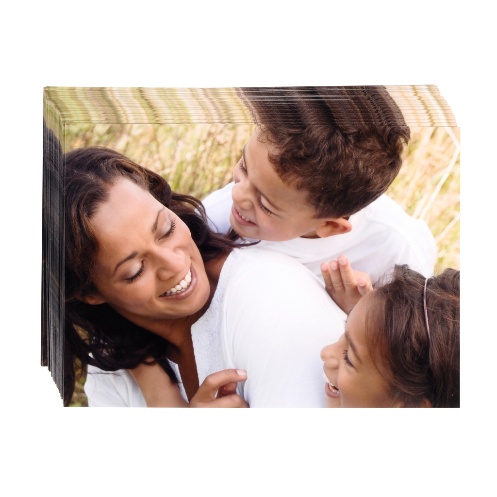 A woman is hugging her two children of different sizes in a field, surrounded by Fuji Personalized Photo Products small format prints.