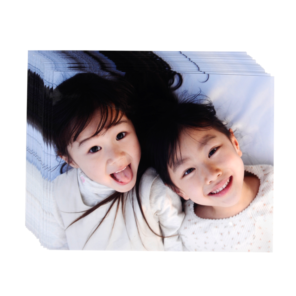 Two young girls laying on a bed with their mouths open, captured in various sizes on Fuji Personalized Photo Products Small Format Prints.