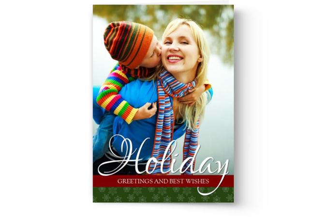 Child in colorful winter clothes kissing a smiling woman on the cheek, with "holiday greetings and best wishes" text below on Photo Book Press's Custom Photo Christmas Card Printing | Design Your Own Christmas Cards.