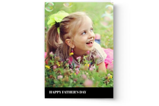A joyful child in a grassy field with the greeting "Happy Father's Day" at the bottom of a personalized Photo Book Press Create & Print Custom Photo Father's Day Card.