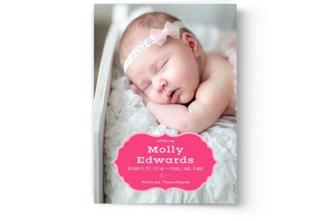 A newborn baby girl is peacefully sleeping on a custom printed white blanket, adorned with a pink headband; a Photo Book Press Birth Announcement Photo Card overlay includes her name and birth details.